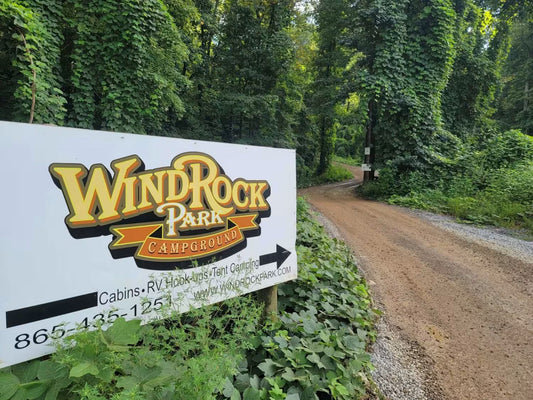 WindRock Park Campground sign at the start of a dirt road surrounded by lush trees.